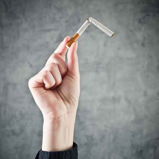 Woman quits smoking and breaking cigarette in half Smoking and Back Pain